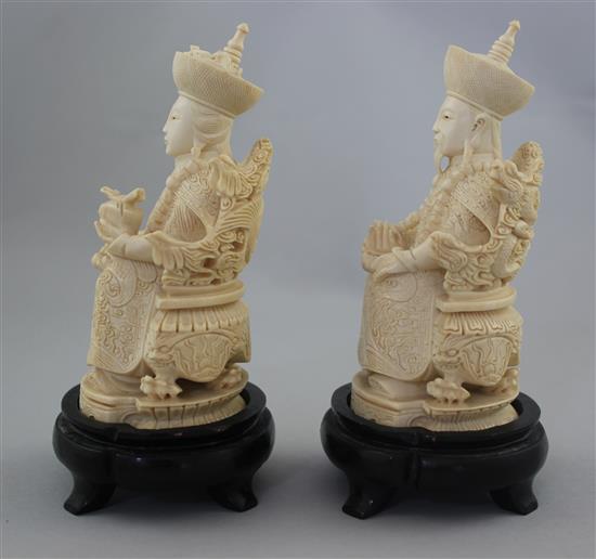 A pair of Chinese ivory seated figures of an emperor and empress, first half 20th century, 13.5cm excl. the wood stands